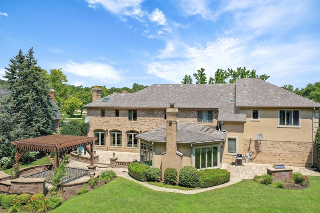 back of property featuring brick siding, a yard, a chimney, a patio area, and a pergola