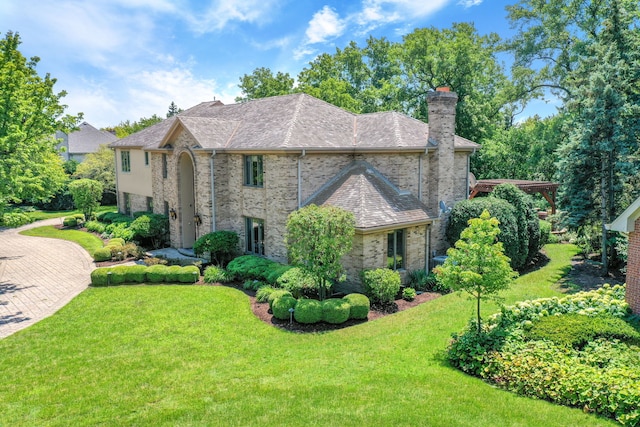 view of front facade with a front yard, brick siding, and a chimney