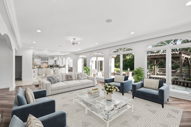 living room featuring arched walkways, ornamental molding, baseboards, and recessed lighting