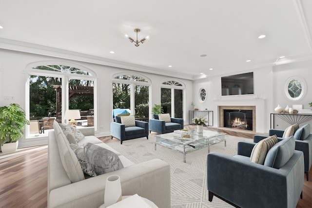 living room with a warm lit fireplace, crown molding, wood finished floors, and recessed lighting