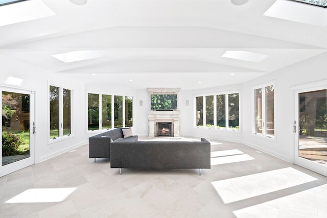 sunroom featuring a warm lit fireplace, lofted ceiling with skylight, and a healthy amount of sunlight