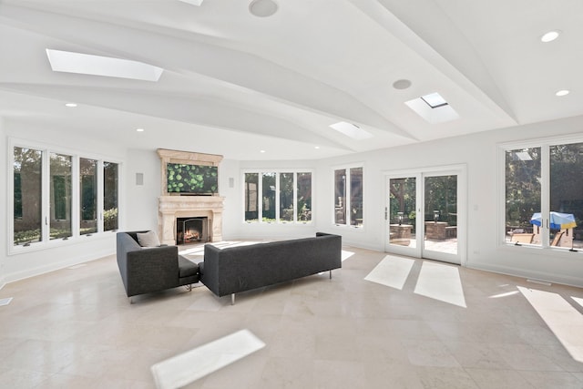 living area featuring a warm lit fireplace, vaulted ceiling with skylight, baseboards, and recessed lighting