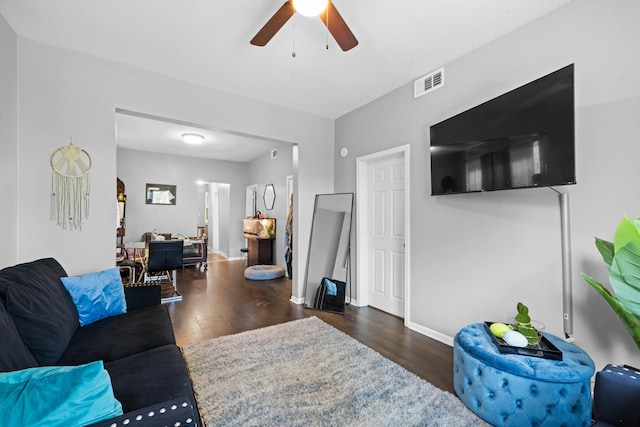 living room featuring ceiling fan and dark wood-type flooring