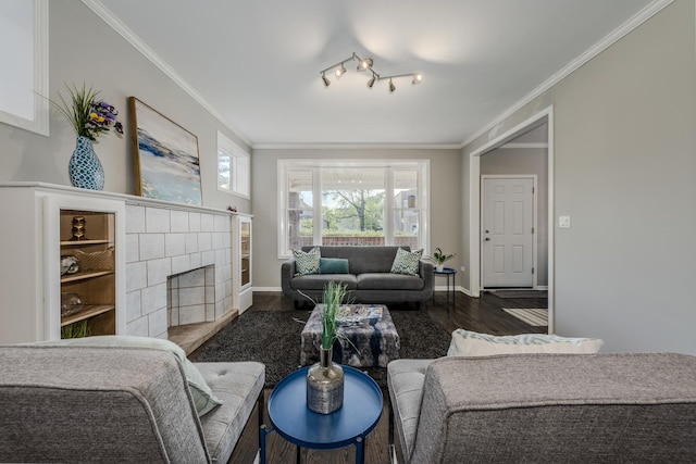 living room with a tile fireplace, dark wood-type flooring, and ornamental molding