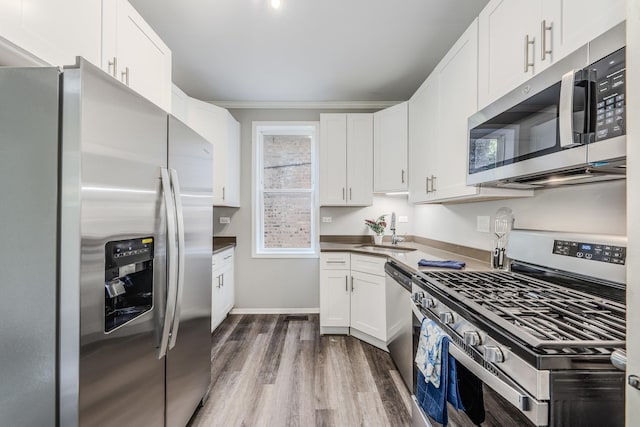 kitchen with sink, appliances with stainless steel finishes, white cabinetry, crown molding, and dark wood-type flooring