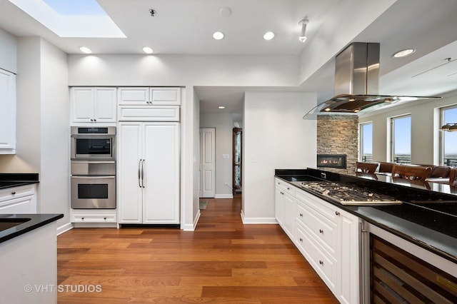 1250 S Michigan Ave Unit 2900, Chicago, IL 60605 - kitchen featuring island exhaust hood, stainless steel appliances, dark countertops, white cabinetry, and beverage cooler