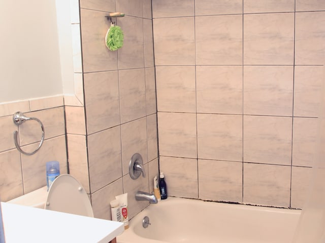 bathroom with vanity, tiled shower / bath, and tile walls