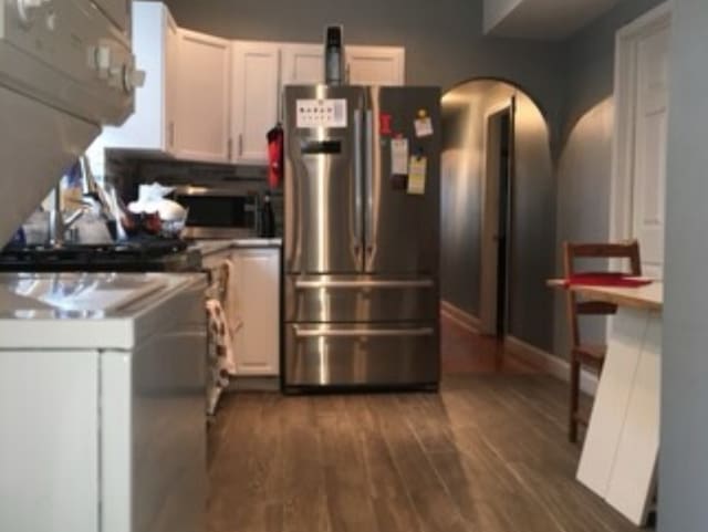 kitchen with appliances with stainless steel finishes, dark wood-type flooring, and white cabinets