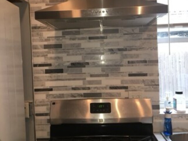 room details with range and wall chimney range hood