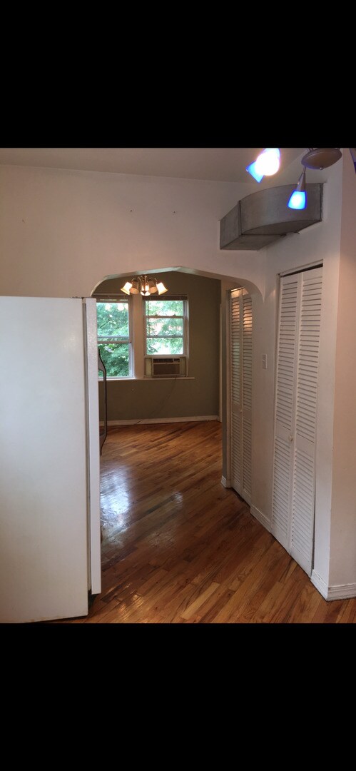 hall featuring hardwood / wood-style flooring, cooling unit, and a chandelier