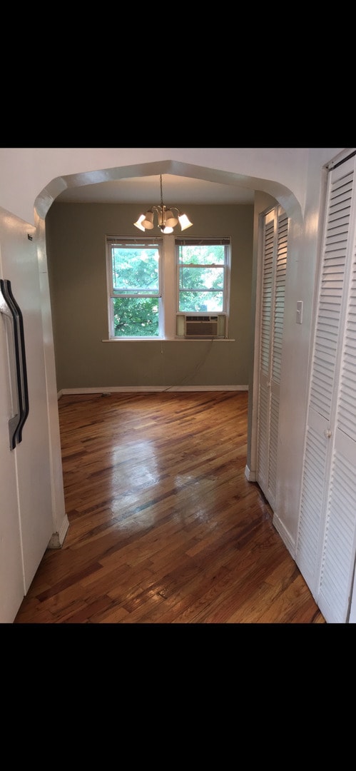 hallway featuring an inviting chandelier, wood-type flooring, and cooling unit