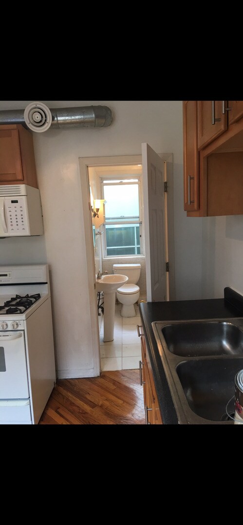 kitchen featuring sink, dark wood-type flooring, and white appliances