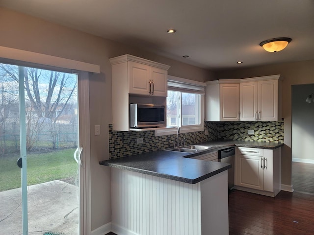 kitchen featuring stainless steel appliances, kitchen peninsula, a healthy amount of sunlight, sink, and white cabinetry