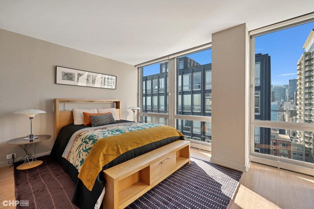 bedroom with light hardwood / wood-style flooring and a wall of windows