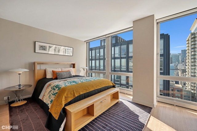 bedroom featuring wood-type flooring and a wall of windows