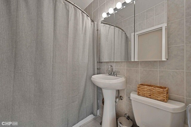 bathroom with tile patterned floors, decorative backsplash, tile walls, and toilet