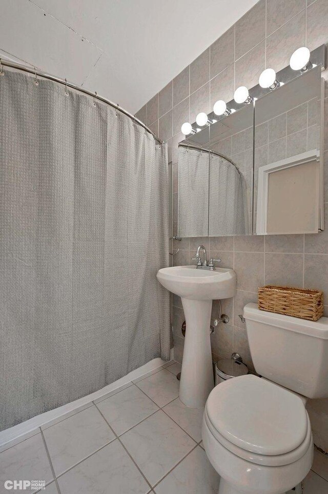 bathroom featuring tile patterned flooring, tile walls, decorative backsplash, and toilet