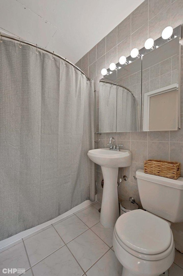 bathroom with a shower with curtain, tile walls, tile patterned floors, and toilet