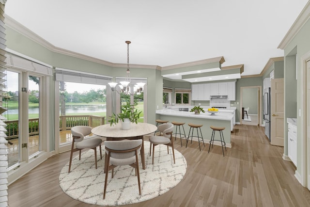 dining space with sink, crown molding, light hardwood / wood-style flooring, a water view, and a chandelier