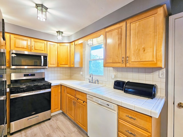 kitchen featuring light hardwood / wood-style floors, appliances with stainless steel finishes, tasteful backsplash, and sink