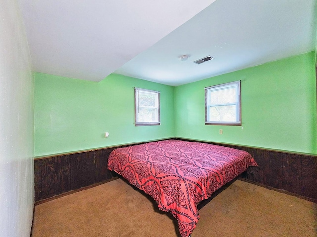 bedroom featuring carpet floors and wood walls