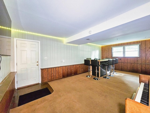 interior space featuring carpet flooring, wood walls, and indoor bar