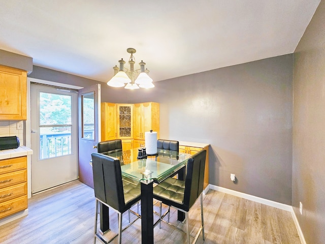 dining room with light wood-type flooring and a notable chandelier