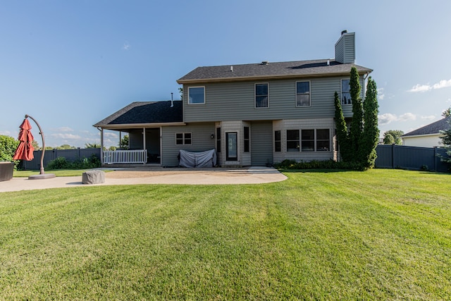 back of house with a lawn and a patio