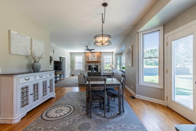 dining space featuring ceiling fan, a fireplace, and light hardwood / wood-style flooring