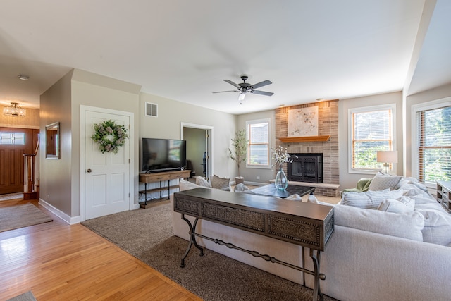 living room featuring ceiling fan, a fireplace, and light hardwood / wood-style flooring