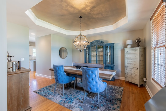 dining space with a raised ceiling, hardwood / wood-style floors, and a healthy amount of sunlight