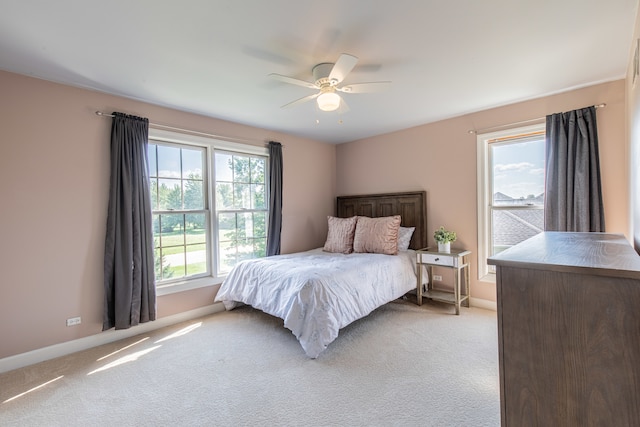 carpeted bedroom featuring multiple windows and ceiling fan