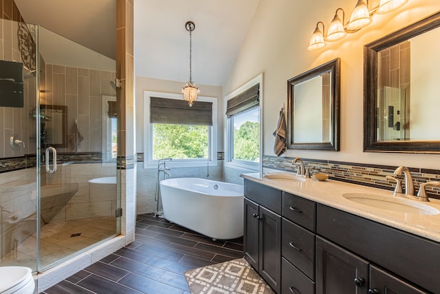 full bathroom with vanity, vaulted ceiling, toilet, tile walls, and independent shower and bath