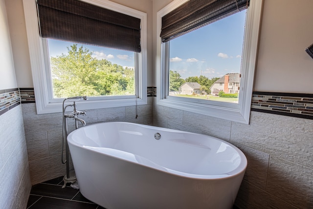 bathroom featuring a bathing tub, tile patterned flooring, and tile walls