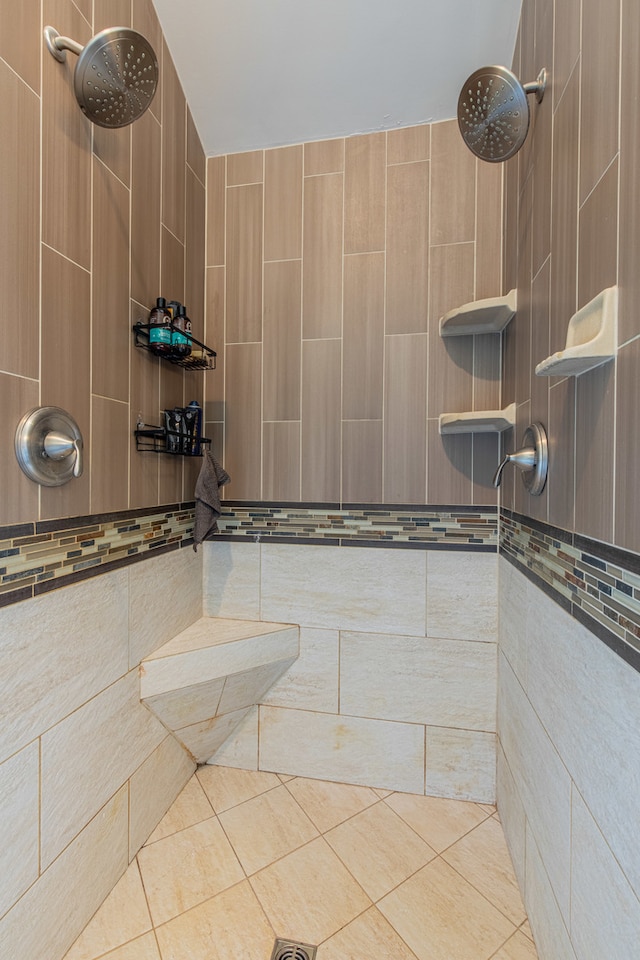 bathroom with a shower, tile patterned floors, and tile walls