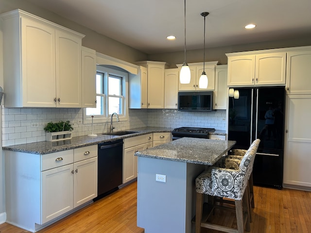 kitchen featuring sink, a center island, light hardwood / wood-style flooring, and black appliances