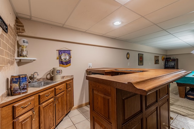 bar featuring butcher block countertops, a paneled ceiling, sink, and light tile patterned floors