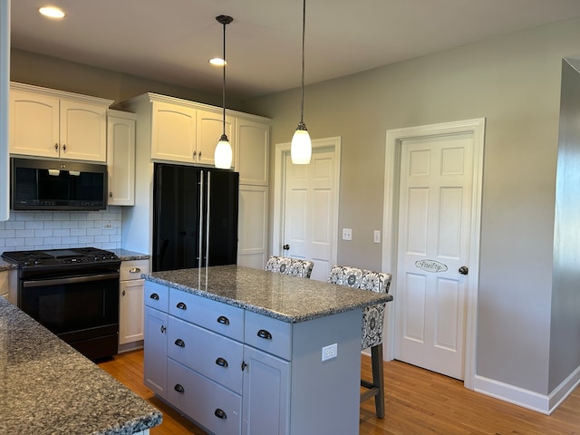 kitchen with black appliances, a center island, light wood-type flooring, and white cabinetry