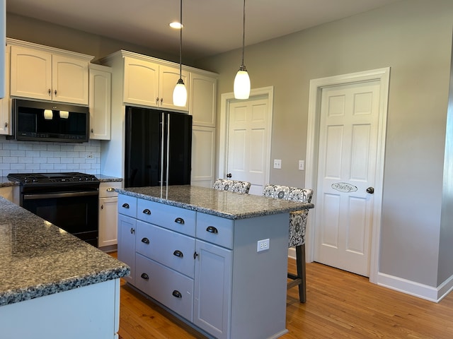 kitchen featuring a center island, light hardwood / wood-style flooring, white cabinetry, and black appliances