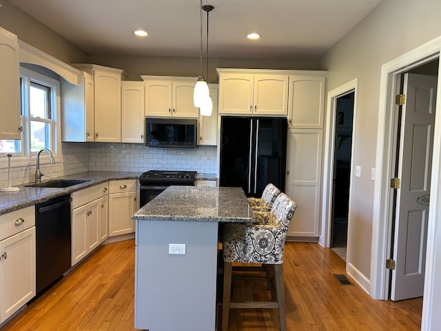 kitchen with sink, a center island, black appliances, and light hardwood / wood-style floors