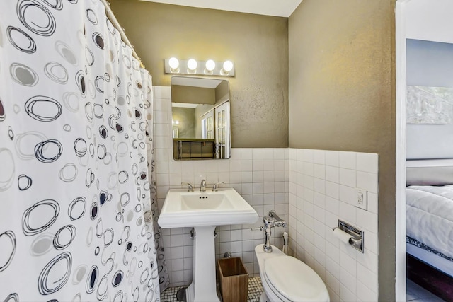 bathroom featuring tile walls and toilet