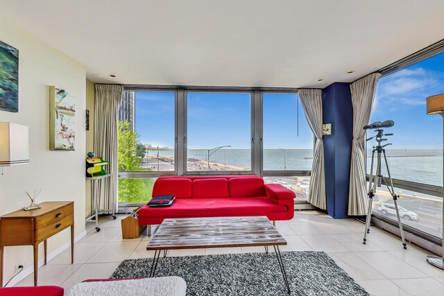 living room featuring a wall of windows, a water view, and light tile patterned floors