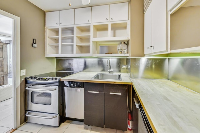 kitchen with sink, light tile patterned floors, appliances with stainless steel finishes, dark brown cabinetry, and white cabinets