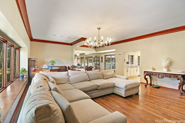 living room featuring crown molding, a chandelier, and hardwood / wood-style flooring