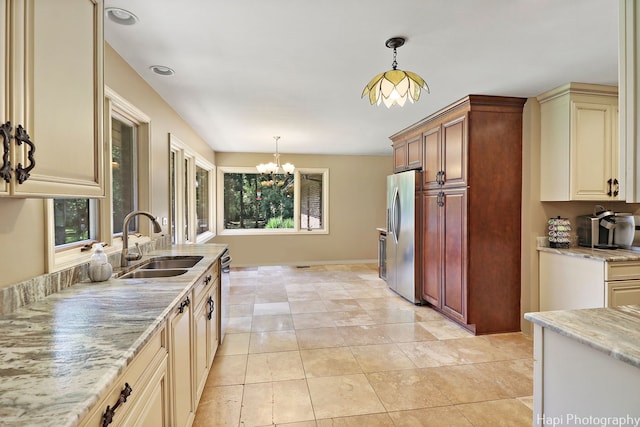 kitchen featuring light tile patterned flooring, cream cabinetry, hanging light fixtures, and sink