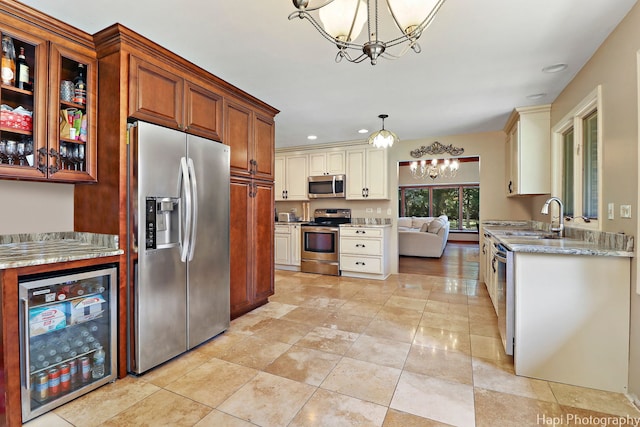 kitchen with stainless steel appliances, sink, pendant lighting, cream cabinetry, and wine cooler