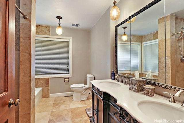 bathroom featuring tile patterned flooring, a bathtub, toilet, and dual bowl vanity