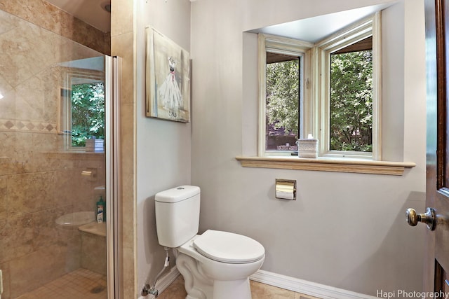 bathroom featuring tile patterned flooring, a tile shower, and toilet