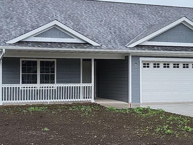 exterior space with covered porch, roof with shingles, and an attached garage