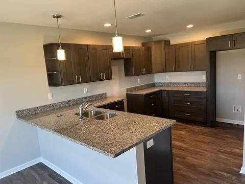 1109 S 2nd St, Oregon, IL 61061 - kitchen featuring stone countertops, a peninsula, dark brown cabinetry, dark wood finished floors, and hanging light fixtures